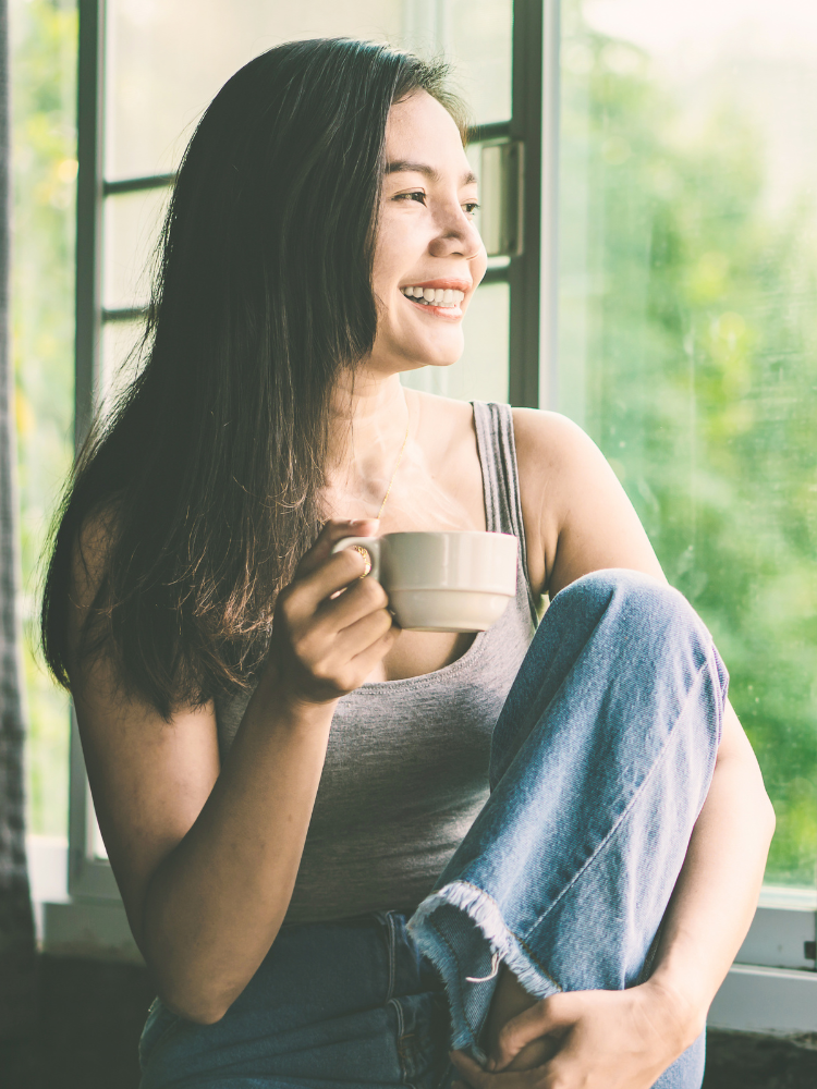 Image of a woman looking out the window and drinking tea